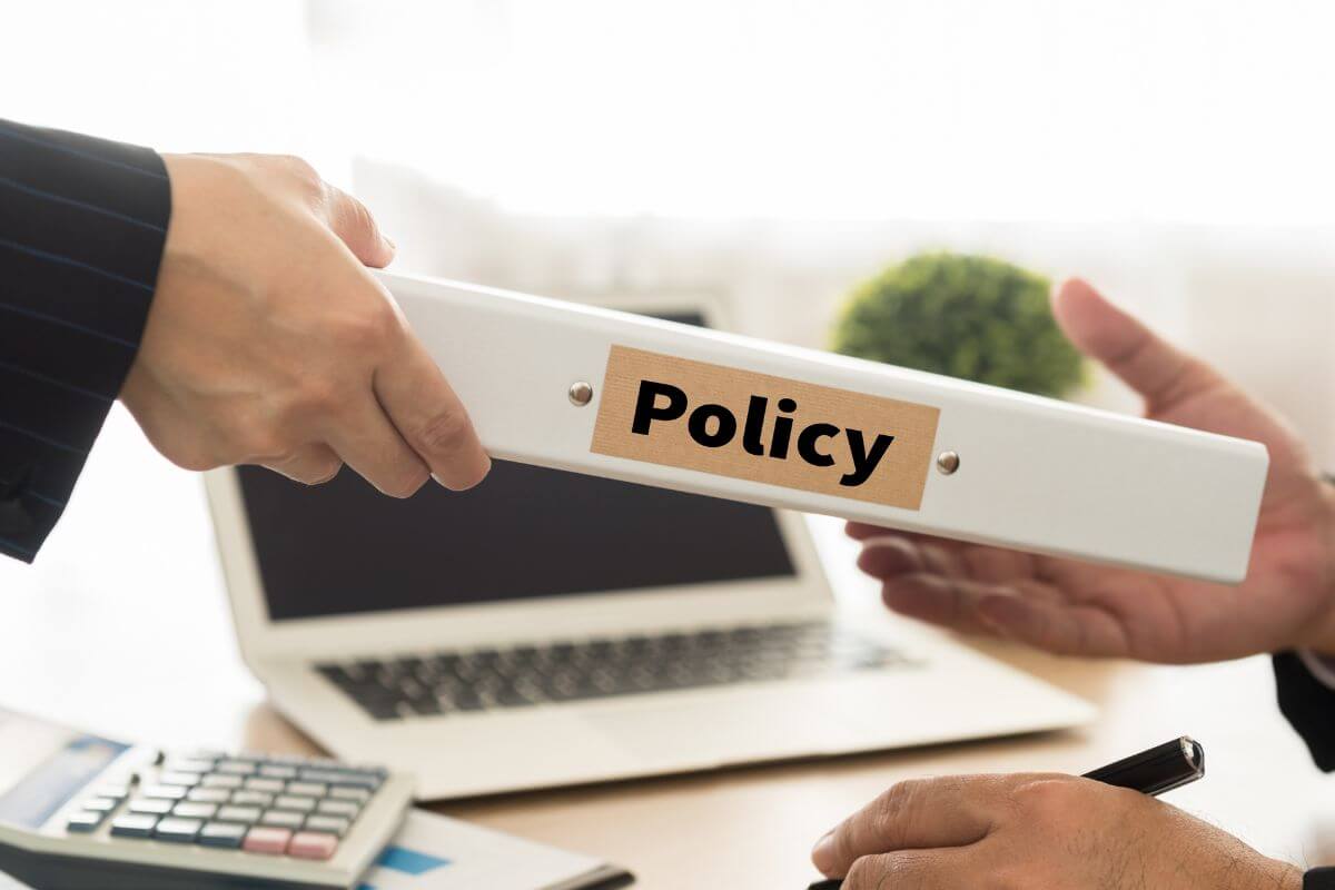 Handing over a book with the word POLICY to another