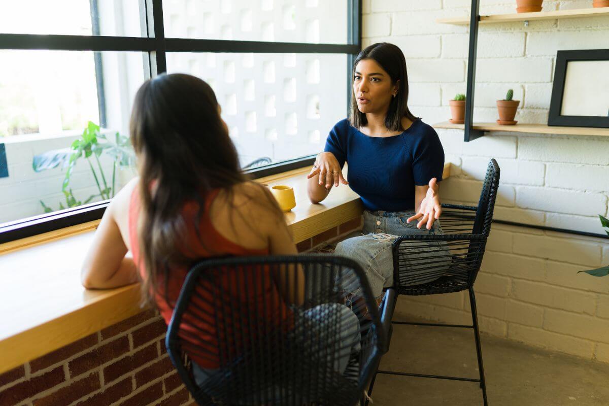 two women sitting in a chair having a conversation