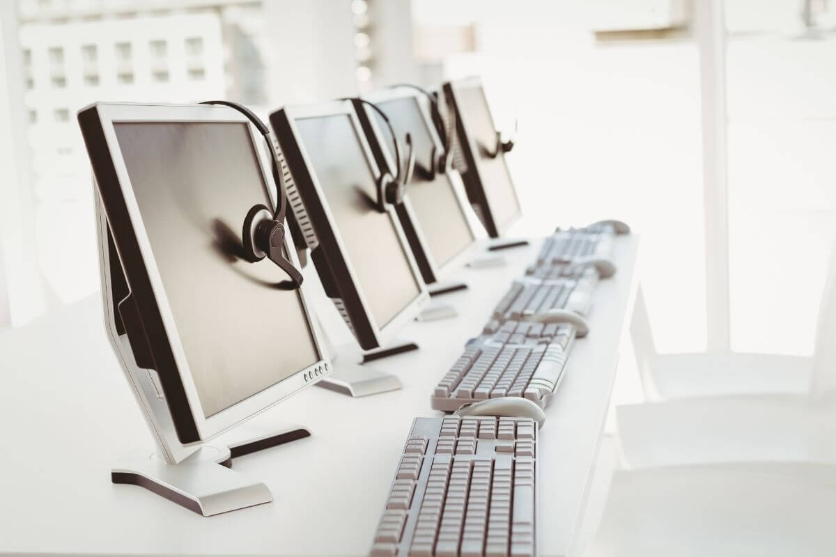 a line of office computers and headsets sitting on each unit