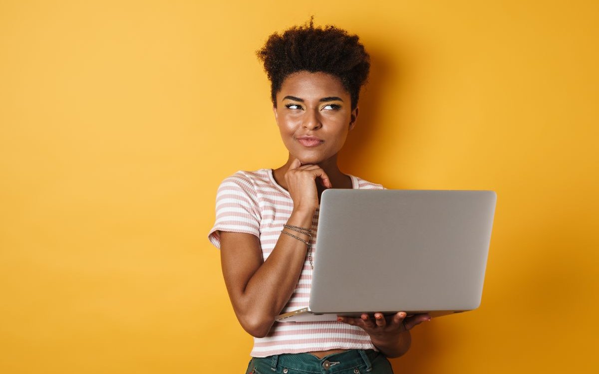 a girl holding a laptop on her left hand and acting like she is thinking something