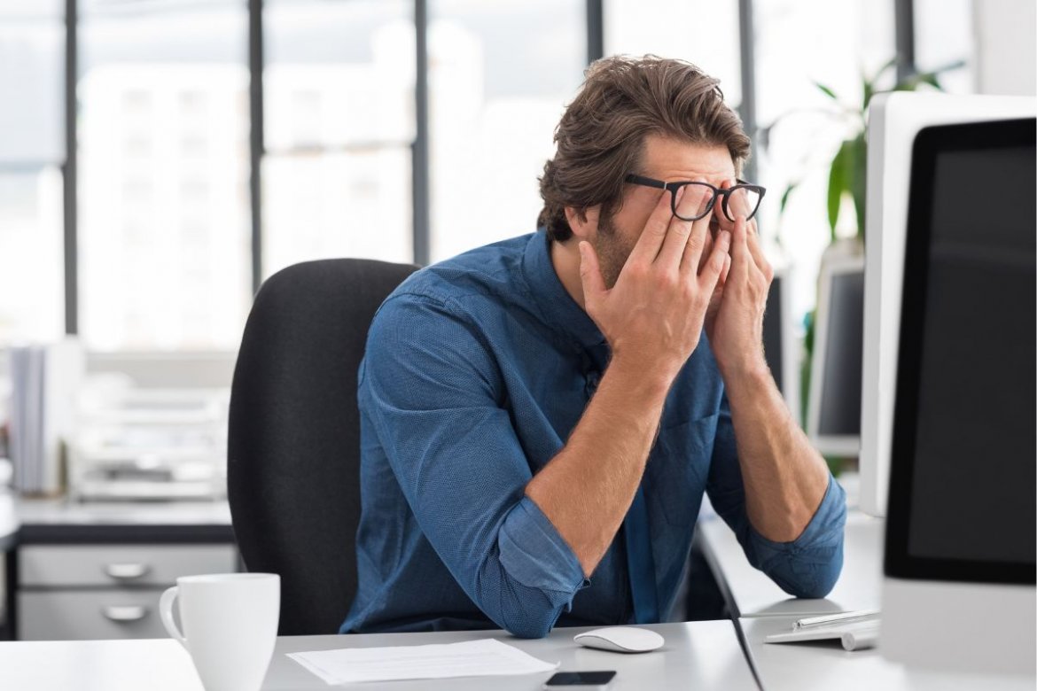 a guy in front of a computer with his palm on his face