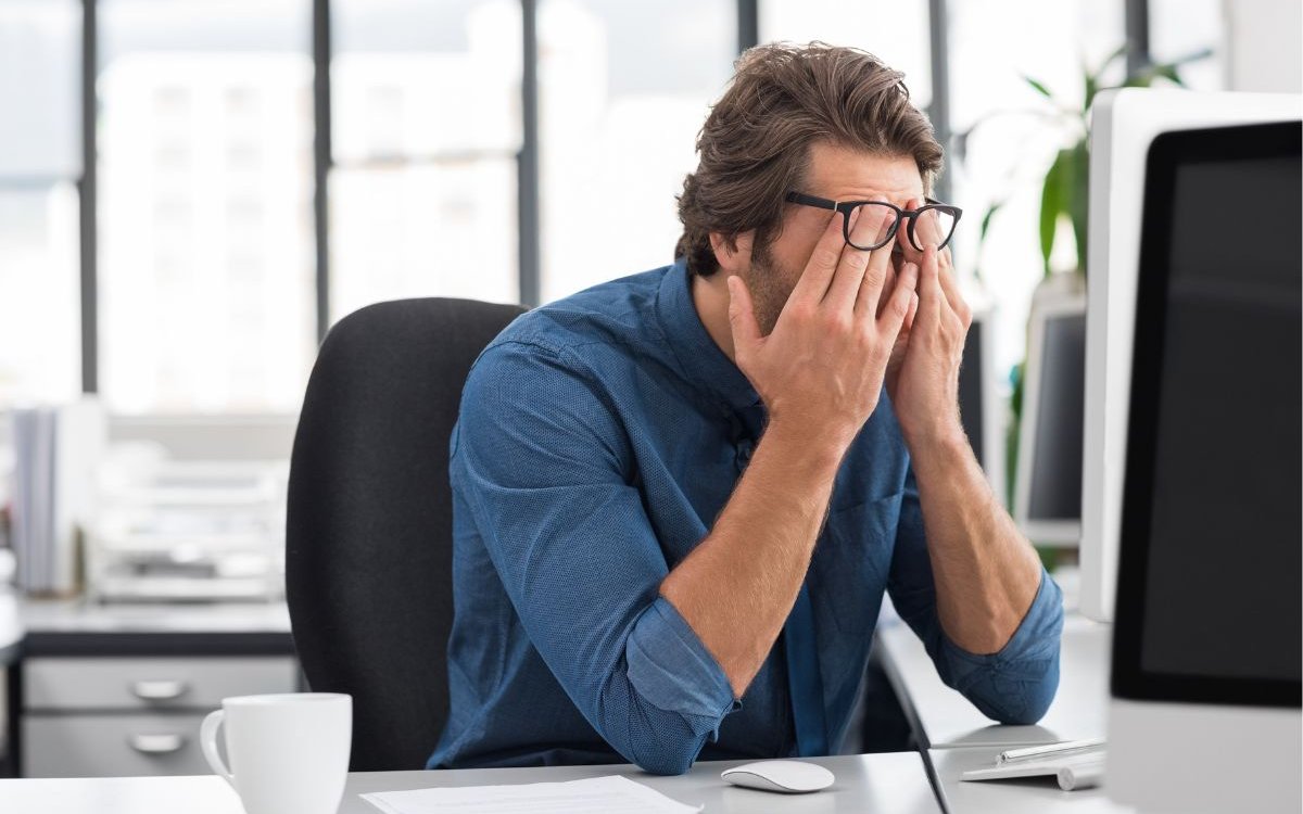 a guy in front of a computer with his palm on his face