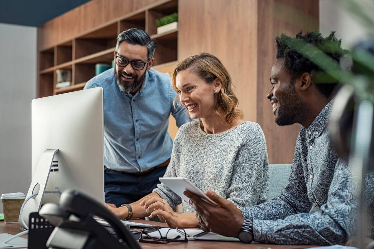 three people having conversation in front of a computer